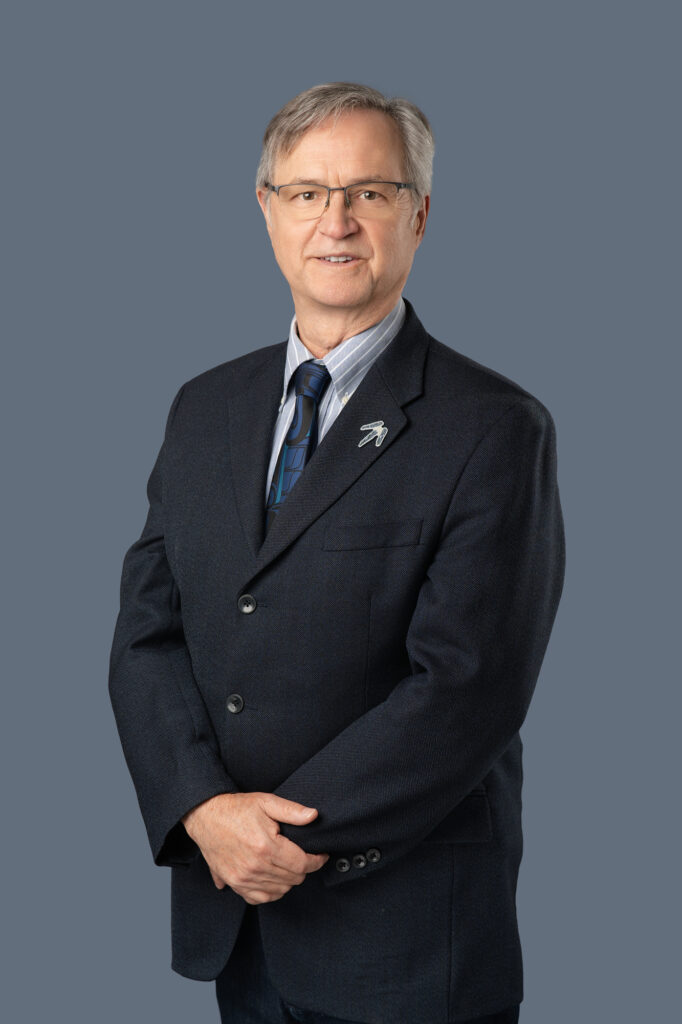 Executive portrait of George Abbott standing with hands crossed