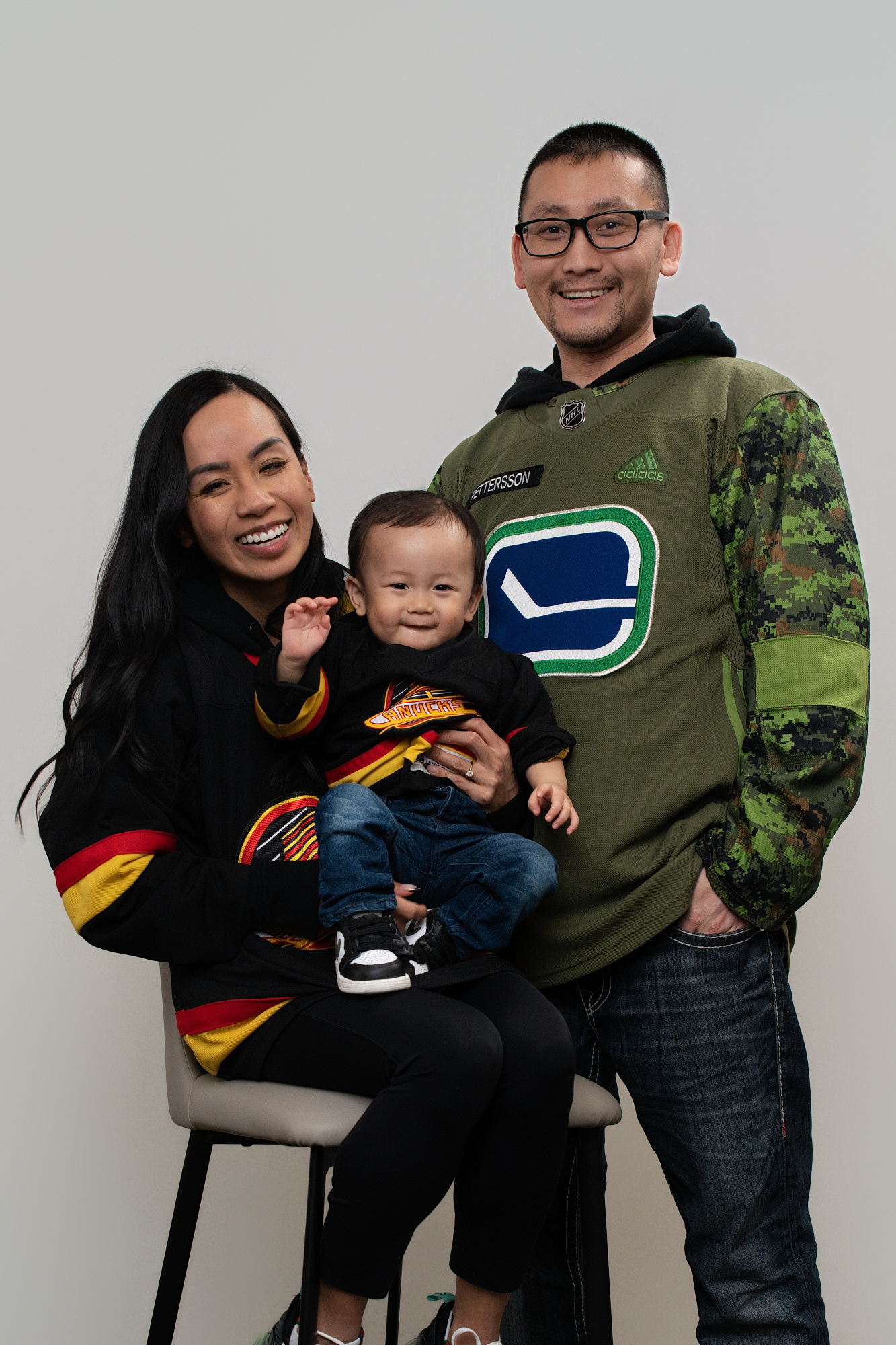 Mini session portrait of parents wearing sports jerseys with their son