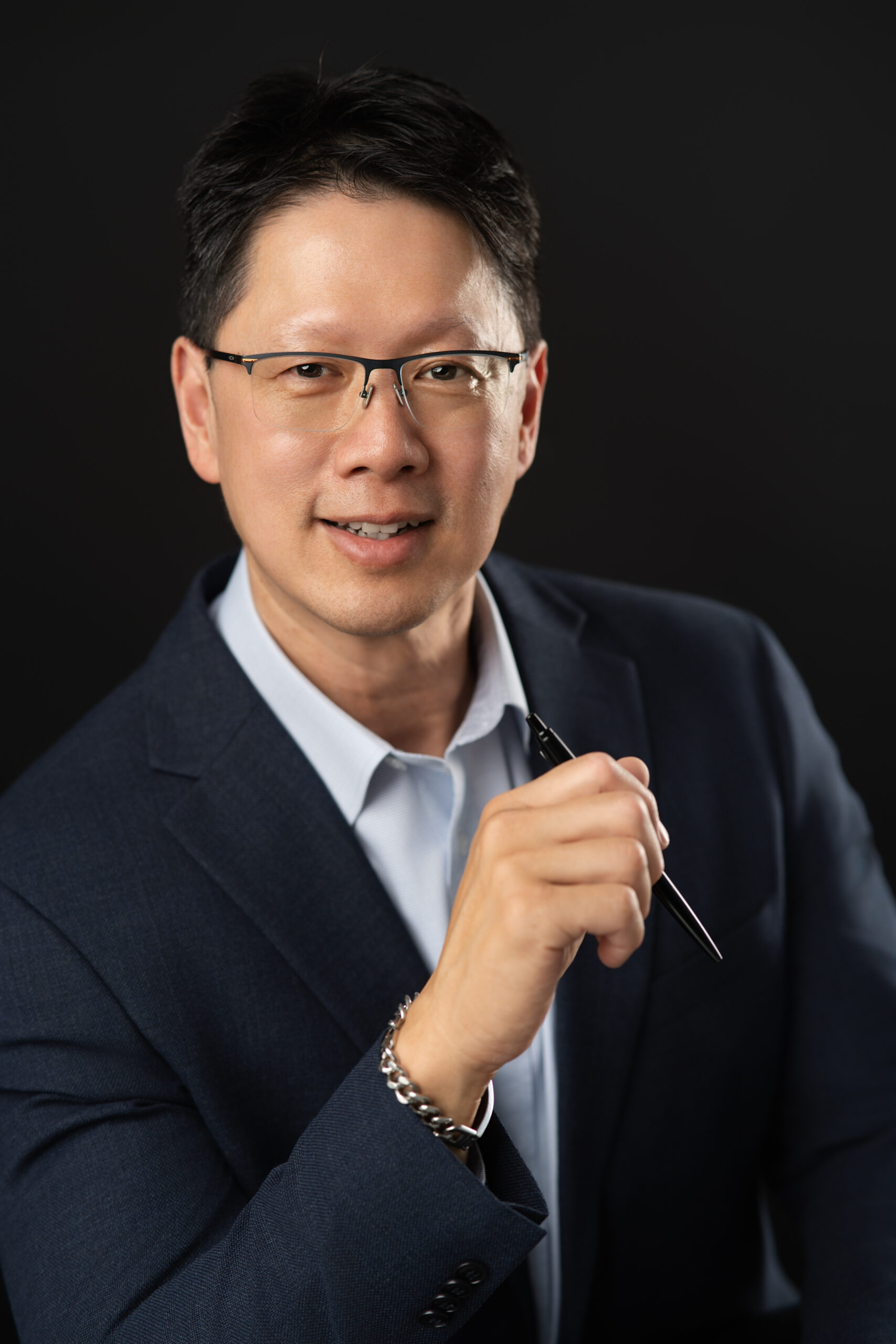Rogers Communication's male territory sales manager in a suit sitting down and holding a pen