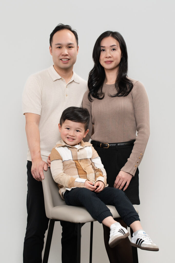 Family portrait of a father and mother standing behind their son sitting on a chair