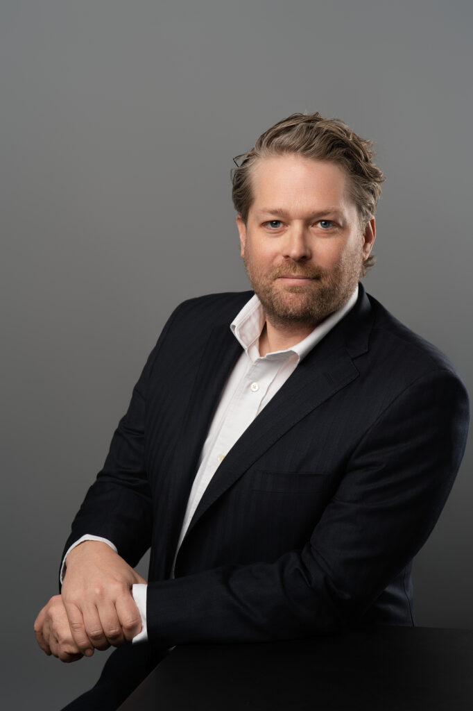 Man in suit against gray background for a headshot.