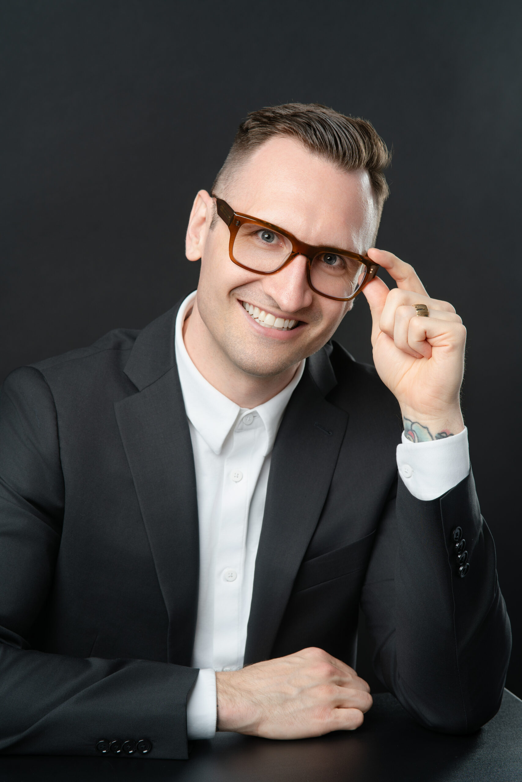 vancouver realtor with right arm on table and the left hand holding onto his glasses